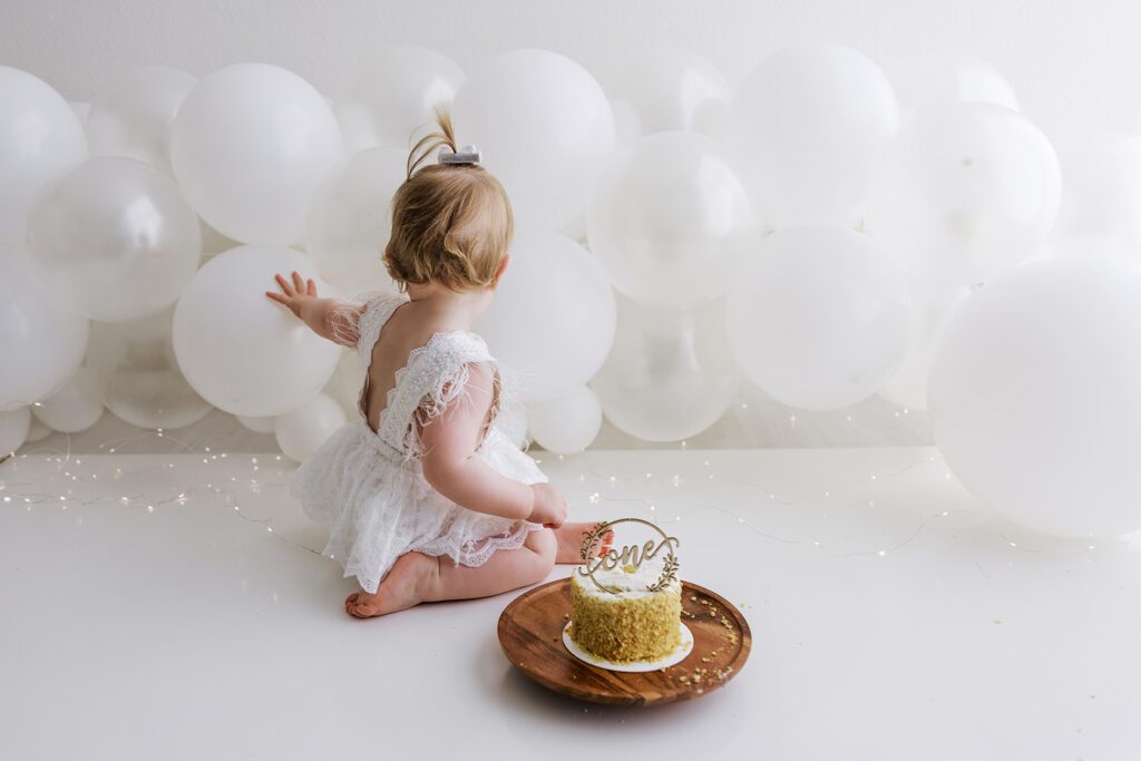 baby playing with balloons and cake
